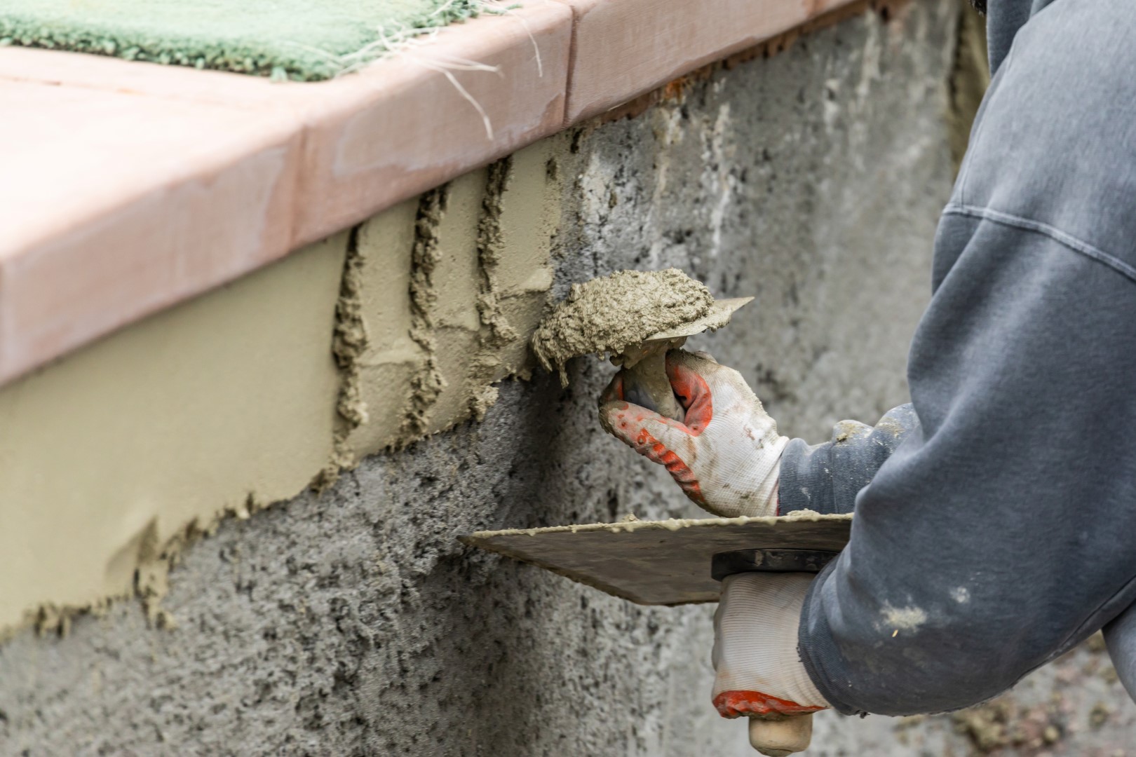 Tile Worker Applying Cement with Trowel at Pool Construction Site.
